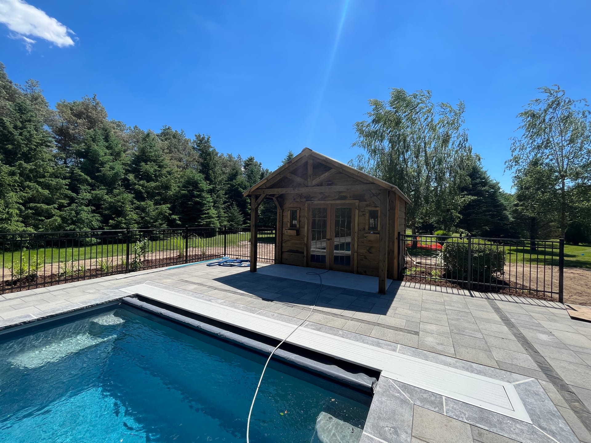 Fiberglass pool with cedar cabana and iron fence in Dorchester Ontario
