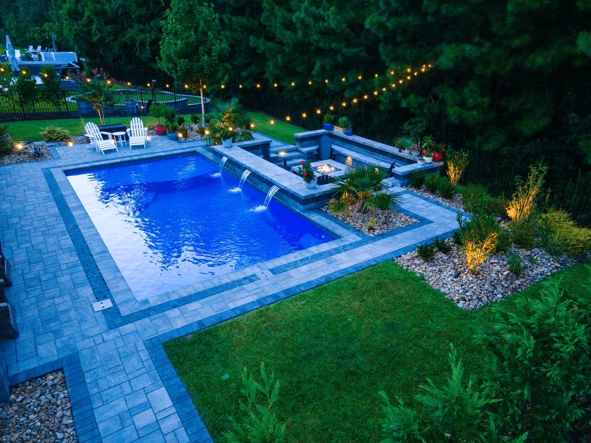 Riverpools fiberglass pool with waterfalls and string lights at twilight